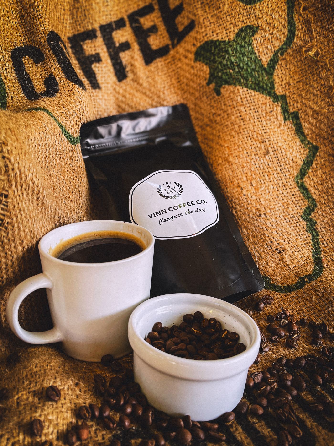 Vinn Coffee bag resting on green coffee beans, next to a cup of brewed coffee